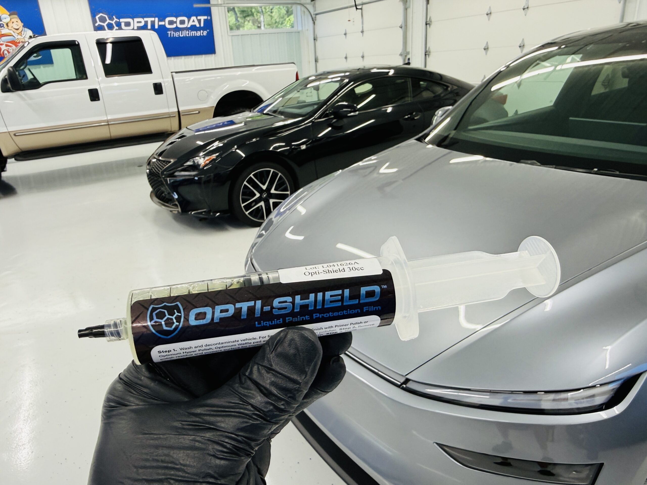 Opti-Shield Liquid PPF syringe in front of a silver Tesla